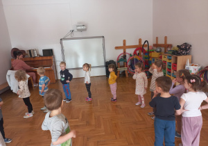 przedszkolaki tańczą przy dźwiękach pianina poruszając się po kole
