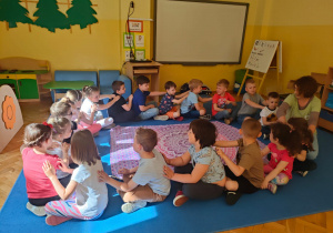 dzieci siedząc w kole wykonują masażyk głaszcząc dłońmi plecy osoby siedzącej przed sobą