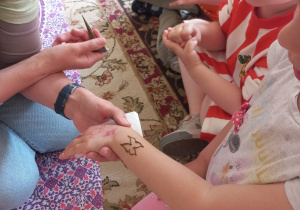 prowadząca maluje tatuaż na ręce dziecka