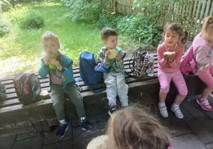 dzieci jedzą na ławeczkach na powietrzu