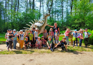 przedszkolaki z nauczycielką stoją przy dinozaurach