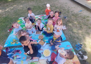 dzieci piknikują w ogrodzie