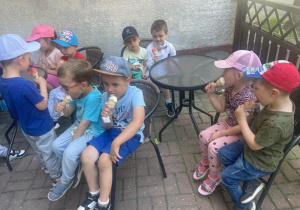 dzieci przed cukiernią jedzą lody