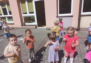 przedszkolaki na tarasie przedszkolnym bawią się bańkami mydlanymi