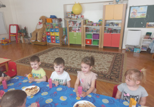 dzieci przy stolikach przy słodkim poczęstunku