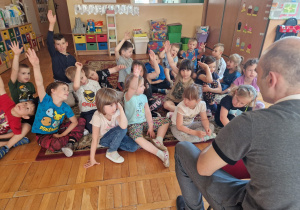 przedszkolaki podnoszą rękę zgłaszając chęć wypowiedzi