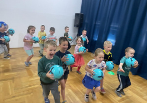 przedszkolaki biegną z piłkami w dłoniach