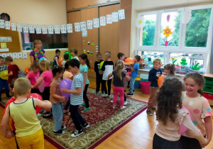 przedszkolaki tańczą w parach z balonem umieszczonym między nimi
