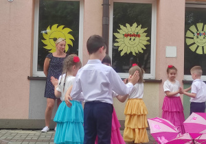przedszkolaki tańczą w parach na obwodzie koła a w środku parasolki
