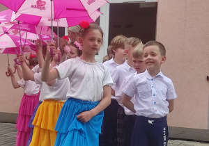 dzieci ustawione w parach jedna za drugą przed tańcem z parasolkami