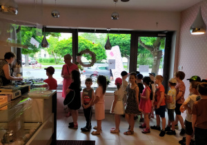 dzieci kupują lody w cukierni stojąc w cukierni