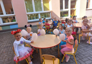 dzieci przy stolikach jedzą różową watę cukrową
