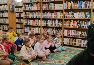 przedszkolaki w bibliotece obserwują cdużego, czarnego psa i pana weterynarza