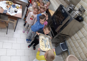 dzieci z tacką pokrojonych jabłek w kuchni przedszkolnej