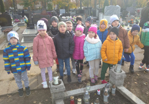 dzieci palą znicze na cmentarzu