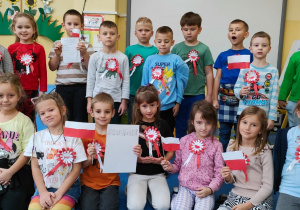 zdjęcie grupowe starszaków z kotylionami i flagami Polski