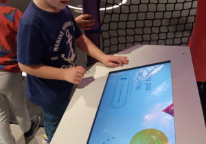 chłopiec przy monitorze ilustrującym obieg Ziemi po orbicie