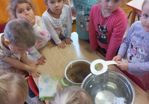przedszkolaki zgromadzone wokół miski z wodą i figurką otrzymaną z wosku