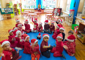 dzieci siedzą na dywanie wokół maskotki Mikołaja