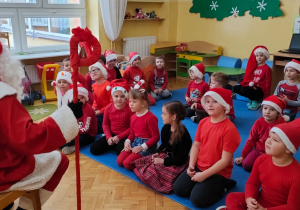 Mikołaj siedzi przed dziećmi i z nimi rozmawia