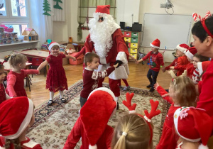 dzieci tańczą w kole z Mikołajem