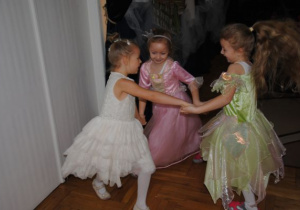 dziewczynki w strojach księżniczek tańczą w kółku