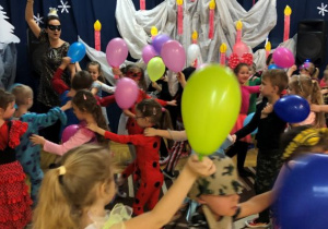 dzieci tańczą w "wężu" z kolorowymi balonami razem z nauczycielką