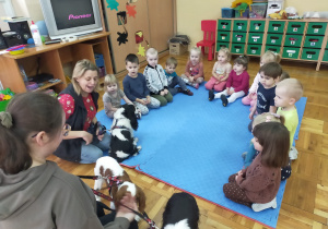 przedszkolaki siedzą w kole i słuchają opiekunek psów