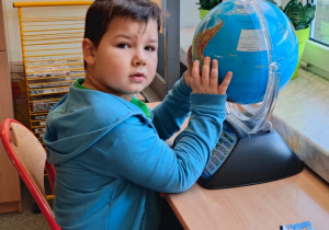 chłopiec siedzi przed globusem