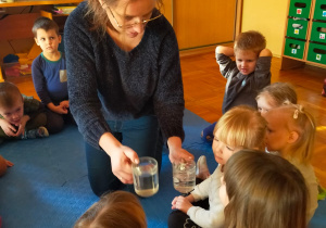 pani psycholog pokazuje dzieciom 2 szklanki z wodą przezroczystą i mętną