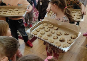 dzieci niosą tacki z ciasteczkami do kuchni aby zostały upieczone