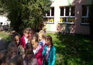 dzieci idą parami po chodniku przed przedszkolem