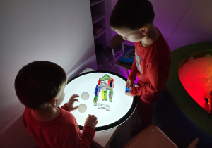przedszkolaki w sali doświadczania świata przy podświetlanym stoliku budują z klocków