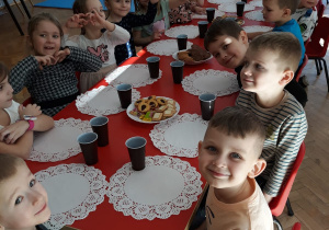 dzieci siedzą przy stolikach podczas słodkiego poczęstunku