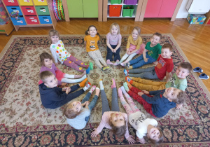 przedszkolaki siedzą w kole i pokazują swoje kolorowe skarpetki
