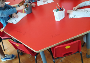 przedszkolaki kolorują kawałki puzzli na stole