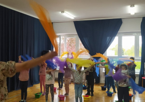 przedszkolaki wymachują kolorowymi chustami nad głowami naśladując ruchy pani Nutki