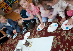 dzieci układają na talerzykach czekoladowe jajeczka