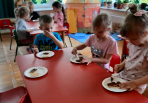 przedszkolaki przy stolikach smarują herbatniki czekoladą