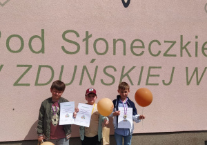 chłopcy z dyplomami, balonami i medalami pod budynkiem naszego przedszkola