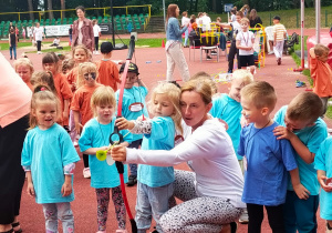 nauczycielka pomaga dziewczynce strzelać z łuku i pokazuje innym