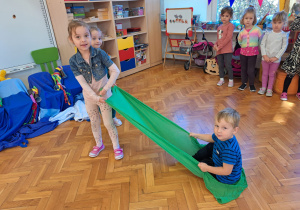 dziewczynki ciągną chłopca na chuście