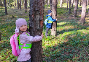 dzieci przytulają się do drzew