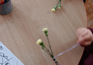 dzieci uczą się wiązać kokardki na kwiatkach