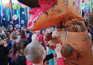 przedszkolaki z maskotką balu dinozaurem