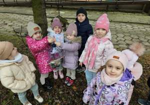 dzieci w ogrodzie trzymają karmnik wykonany z butelki