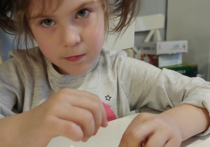 dziewczynka w kitkach układa wzory z klocków na plastikowym jajku
