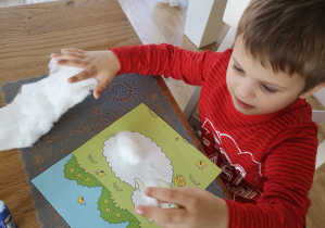 dziecko przykleja watę na kontur baranka
