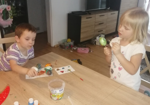 dzieci malują jajka przy stole w pokoju