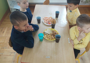 chłopcy siedzą przy stoliku podczas poczęstunku